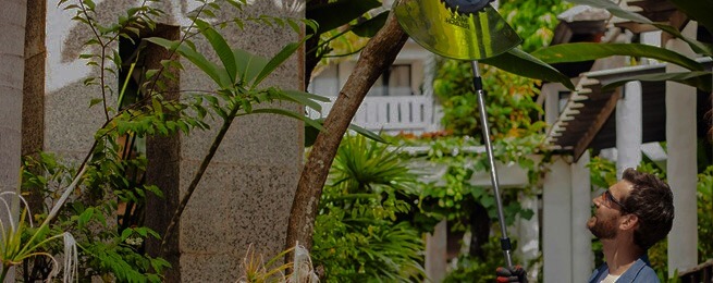 A man using Maxreach tools to saw a branch
